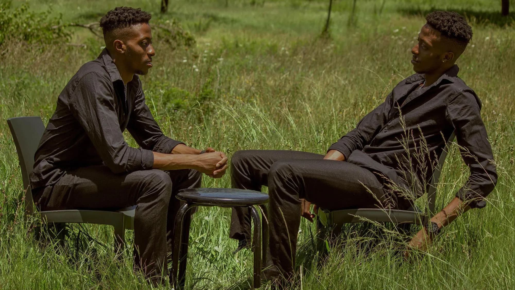 Sihle seated at a small table in long grass