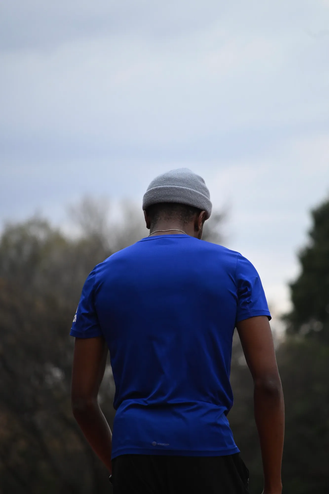 Sihle seen from behind in a blue tee, looking out over trees