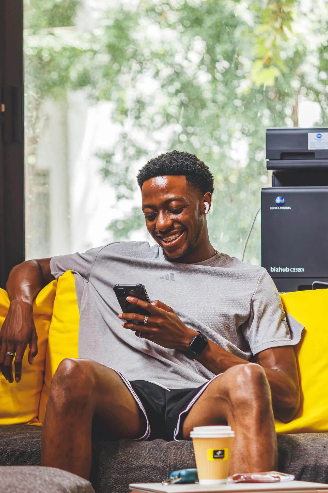 Sihle relaxed on a couch with his phone and laptop